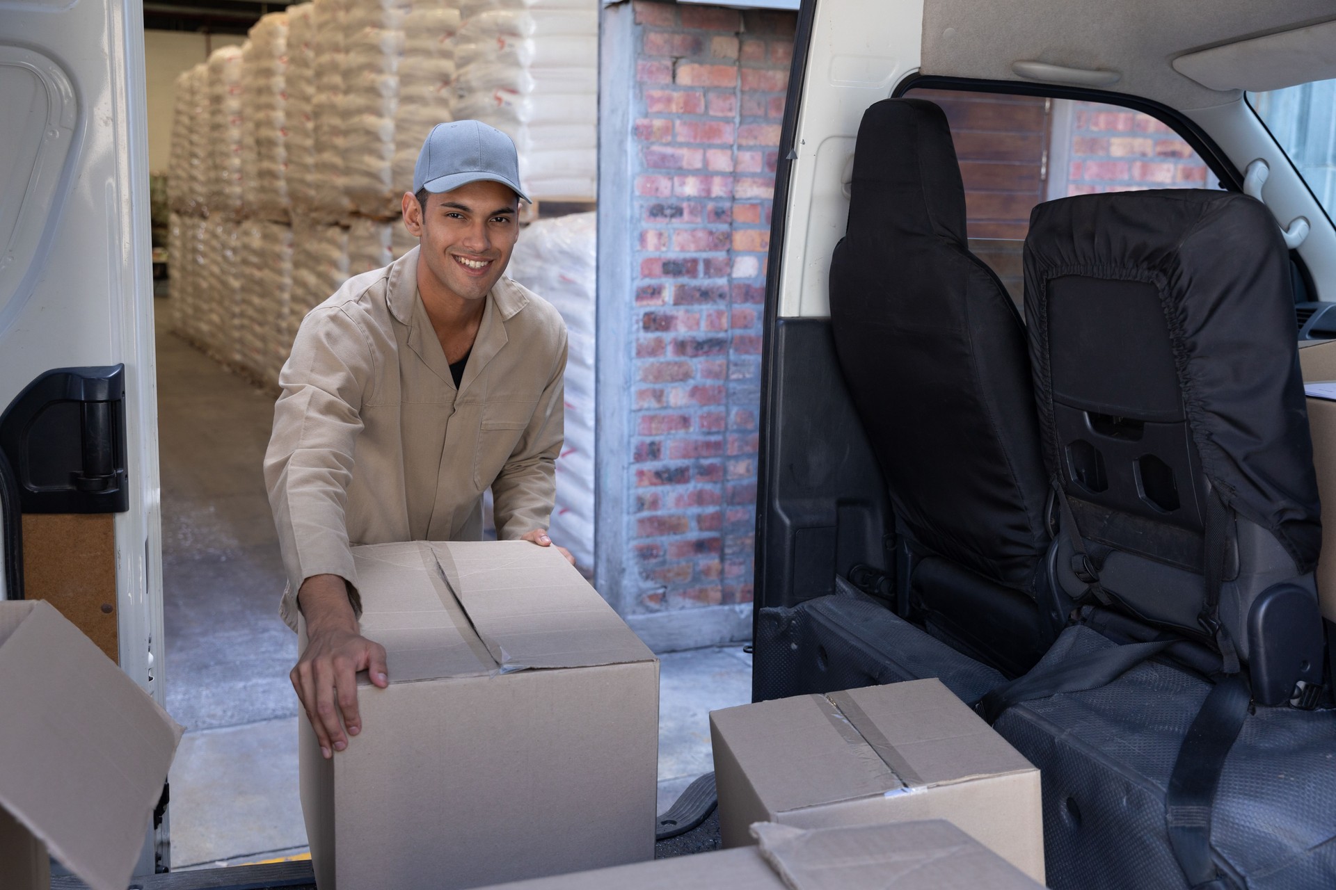 El repartidor descarga cajas de cartón de una furgoneta fuera del almacén