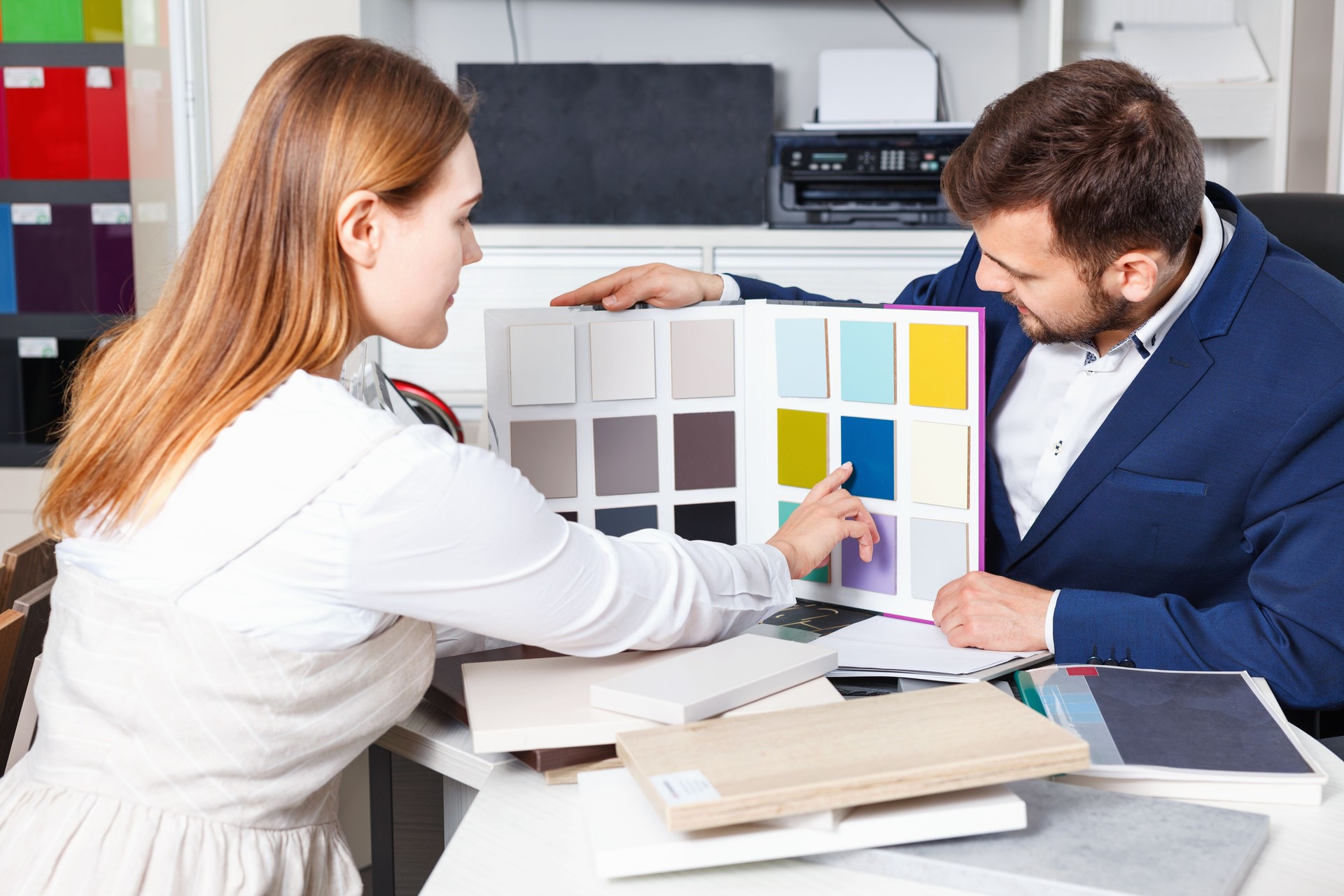 Vendedor competente en showroom ayudar a joven mujer cliente elegir materiales de los muebles de su apartamento